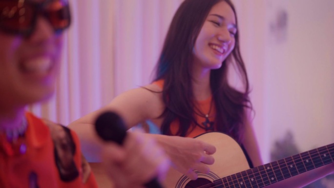 两位快乐的艺术家在一个私人的家庭晚会上与朋友们在舞台上弹吉他和唱歌。
