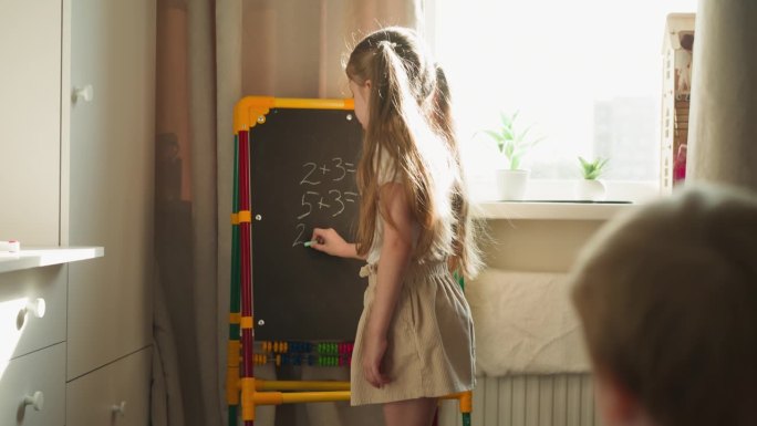 女孩在黑板上写数学题教弟弟