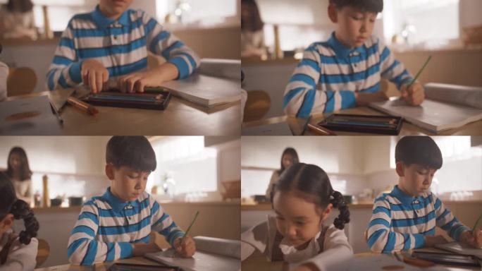 在母亲准备早餐的时候，坐在餐桌边画画、写字的韩国孩子的肖像。可爱的孩子在上学前等待营养餐的完美父母