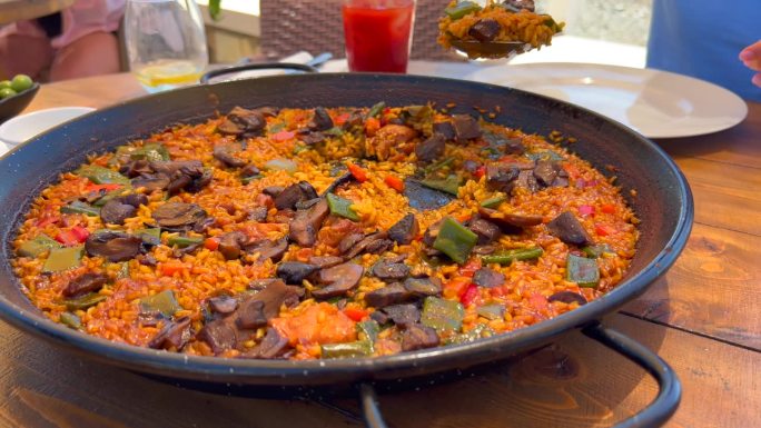 在餐厅用大勺子舀传统的西班牙海鲜饭配蔬菜，美味的蔬菜米饭，Marbella西班牙，4K镜头