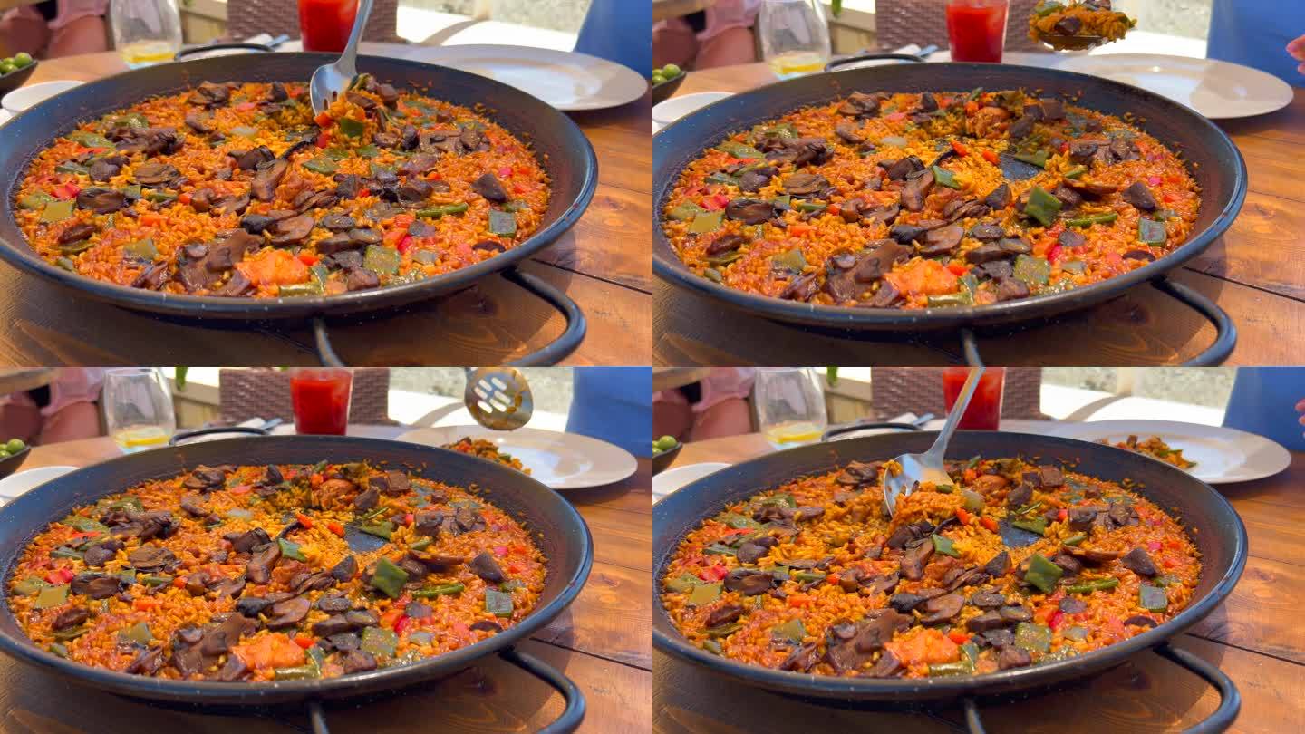 在餐厅用大勺子舀传统的西班牙海鲜饭配蔬菜，美味的蔬菜米饭，Marbella西班牙，4K镜头