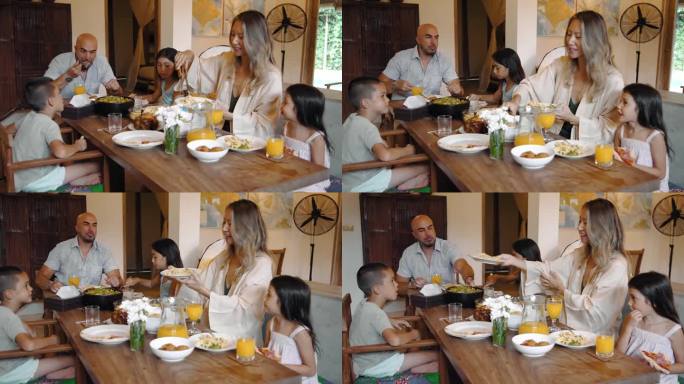 一个快乐的家庭，男人和女人带着孩子在家里吃节日的食物。亚洲妻子为小孩和英俊的丈夫做饭。现代室内的母子
