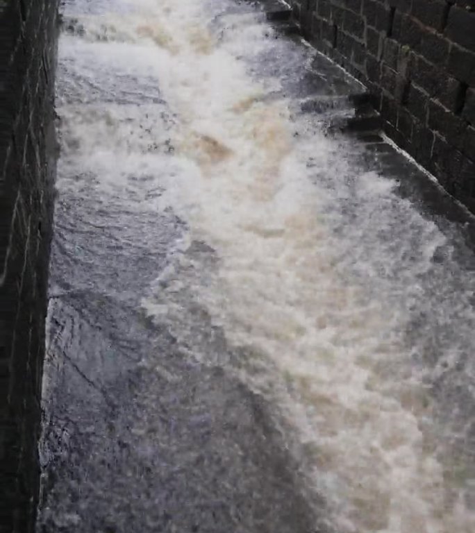 雨水汹涌地冲过这条人工河道，其力量被巨大的水量放大了。