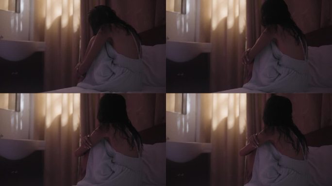 女人抱着膝盖躺在床上的背影