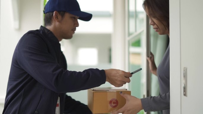 快递员将一个包裹送到客户手中，并在智能手机上签字接受。