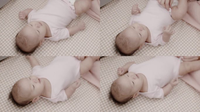 亚洲新生婴儿被母亲盖在床单上穿衣服。父母用爱照顾他们的孩子。