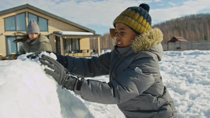 多民族儿童在阳光明媚的冬日制作雪堡