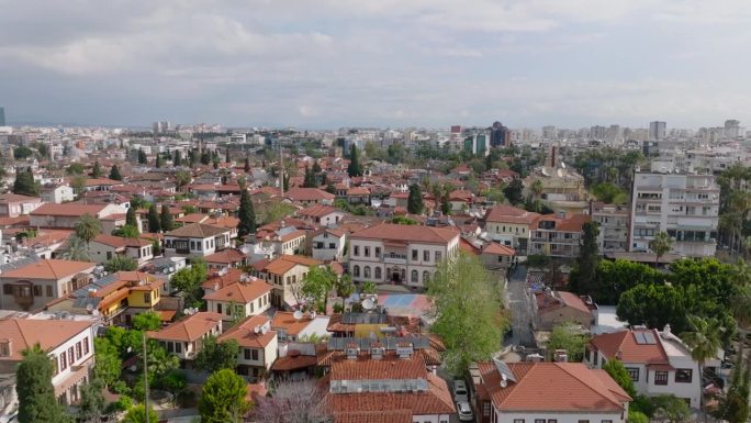 飞机飞过城市居民区的传统房屋。背景中住宅小区的多层公寓楼。土耳其安塔利亚