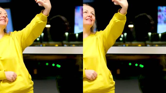 一位女士在机场拿着行李箱用手机自拍亮黄色西装漂亮的中年金发美女在晚上的街上靠窗站着等飞机