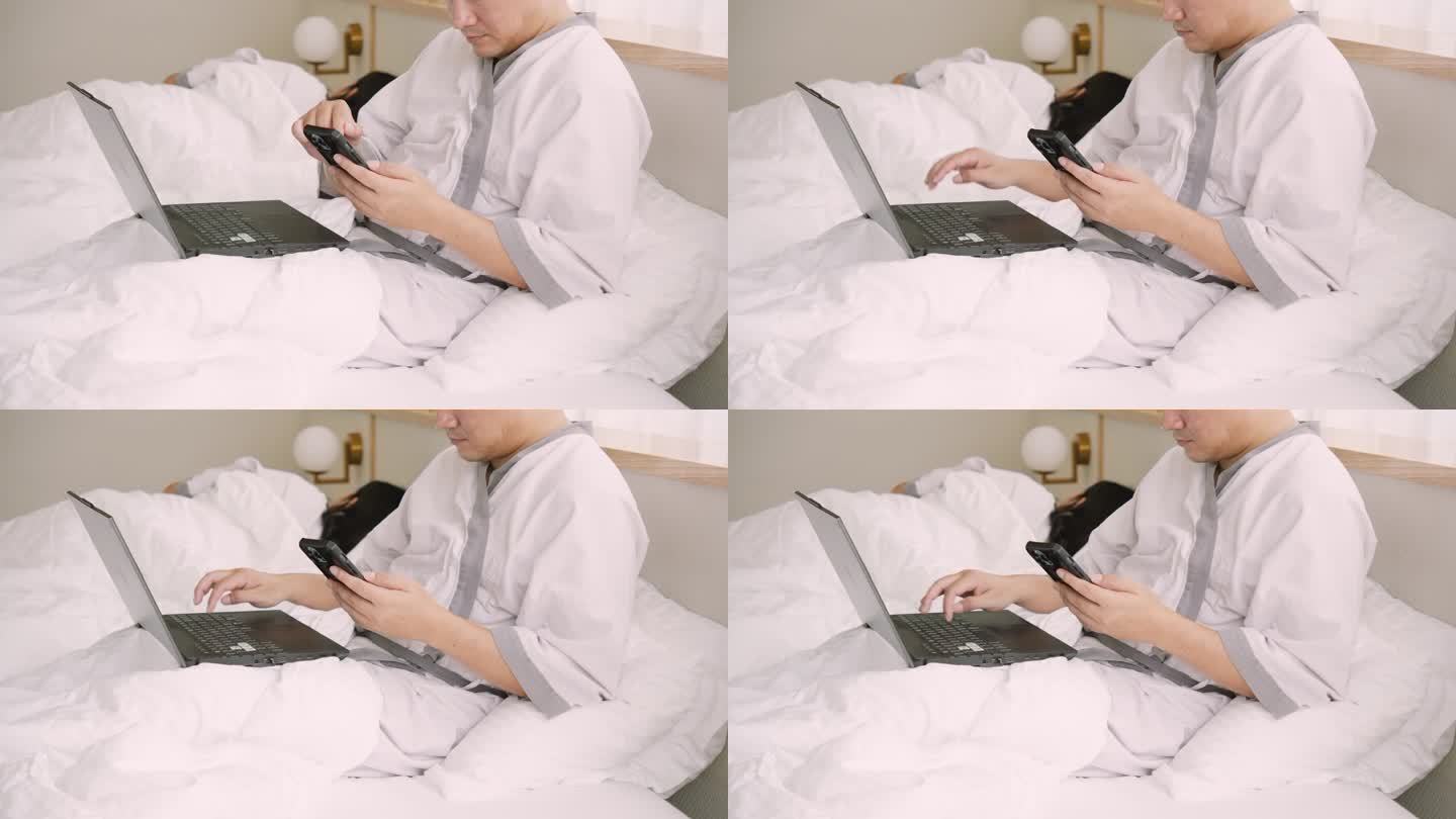 他使用笔记本。在床上工作一对夫妇在卧室里放松