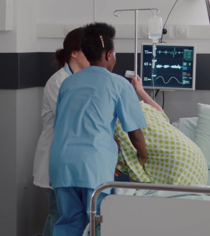 垂直视频:医疗小组检查病人的生命监测心率帮助输液袋