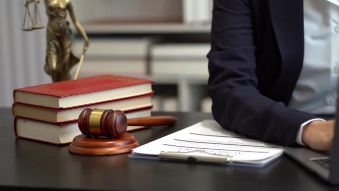 正义与法律概念。女法官在法庭上敲着木槌，在阳光下的木桌上用数码平板电脑工作。