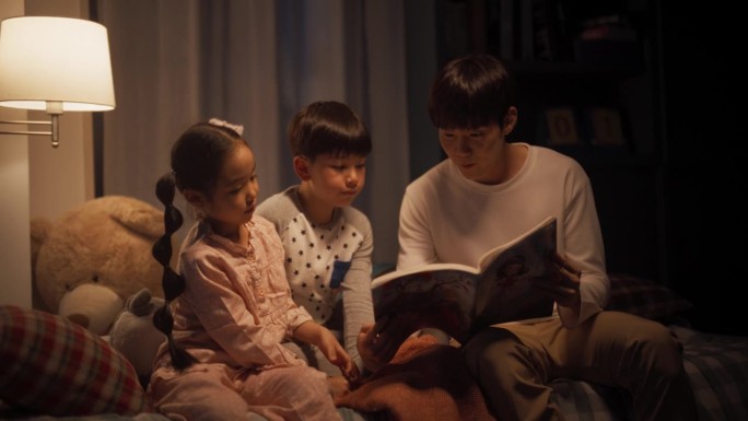 两个活泼的孩子和他们的父亲在睡觉前读书给他们听时的对话画像。可爱的韩国孩子不准备睡觉，和他们的男性父