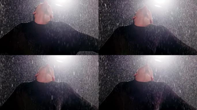 男子张开双臂，头向后仰在雨中
