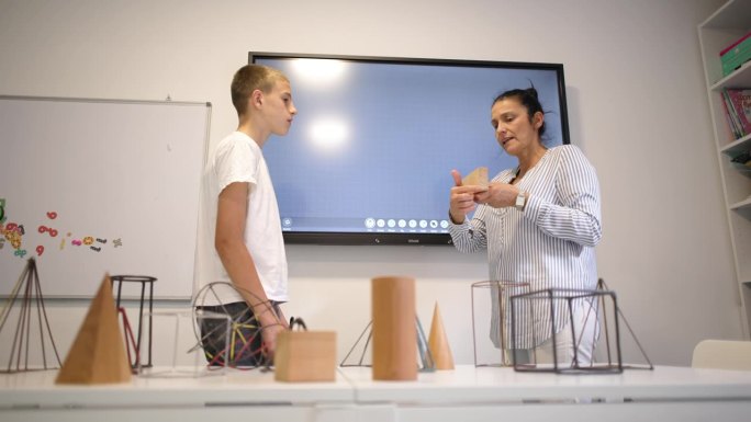 在一所私立学校的教室里，一名白人女几何老师正在和一名男小学生进行一对一的教学