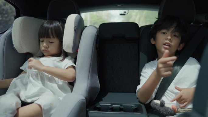 一个小男孩和一个小女孩在汽车后座上唱歌，看起来很开心。