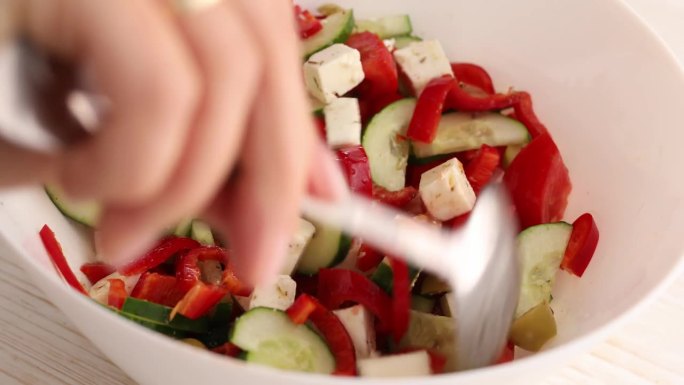 用勺子把奶酪、橄榄、西红柿和黄瓜拌成沙拉。