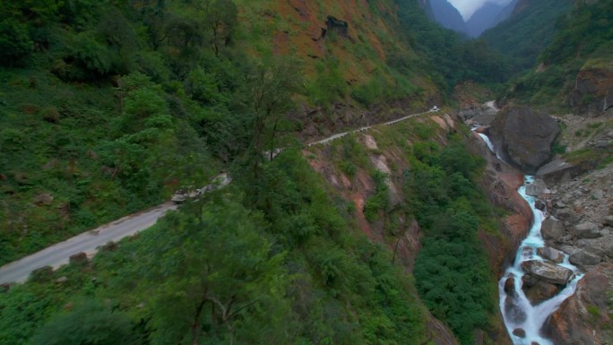 航拍图两辆车通过狭窄的砾石山路。公路旅行围绕喜马拉雅山脉。安纳普尔纳环行。尼泊尔的安全和道路概念。