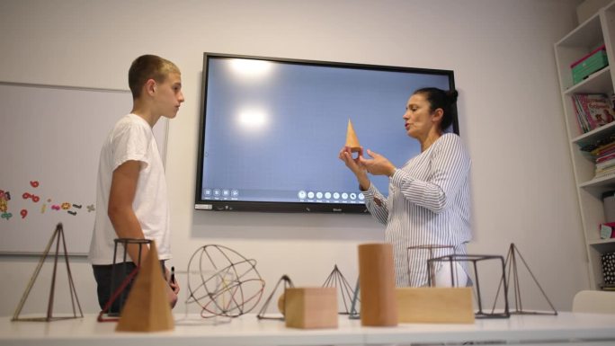 在私立学校的教室里，一位白人女几何老师正在和一名男小学生进行一对一的教学