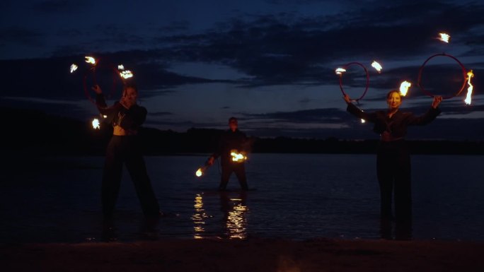专业的马戏团表演者在夜晚的海滩上用火表演，令人惊叹的火焰表演