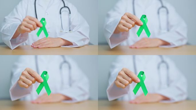 手持绿色丝带的妇女，为九月的世界淋巴瘤意识，世界精神卫生日，肝癌，胆囊癌，胆管癌，宫颈癌，肾癌。保健