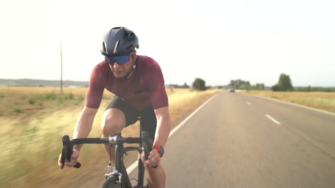 中景:一名成年男性骑自行车者在乡村公路上加速他的自行车——成年人骑自行车的视频