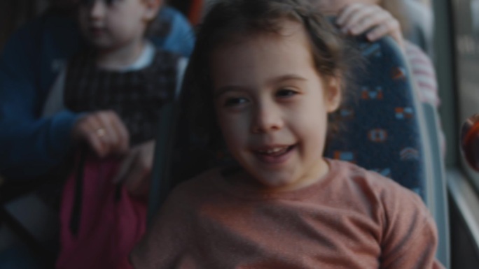 一个可爱的小女孩微笑着，享受着乘坐公共汽车的乐趣