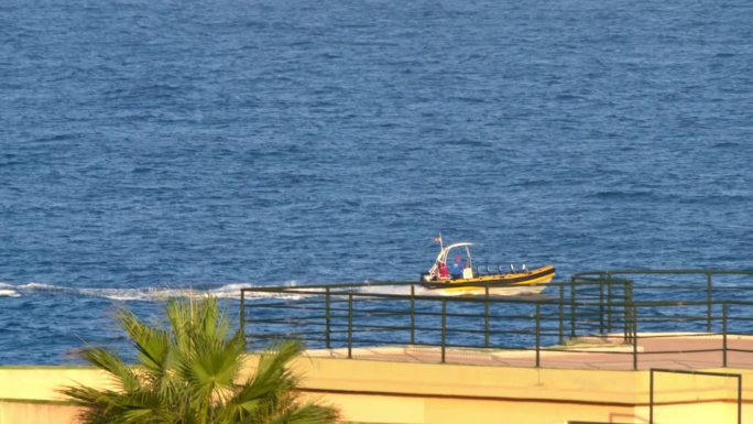 一艘带篷的黄红色摩托艇在波涛起伏的海面上滑行。