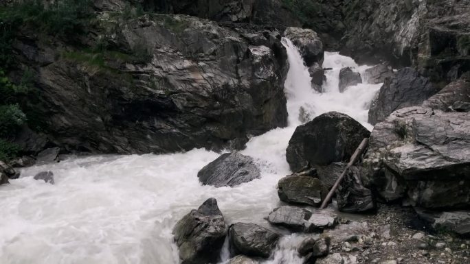 静拍强大的瀑布，岩石，灰色的山脉，湍急的河水