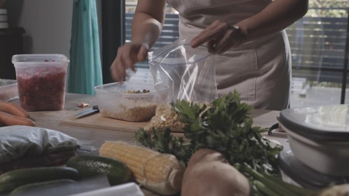 一名妇女在为冬天保存食物时将玉米放入塑料冷冻袋中