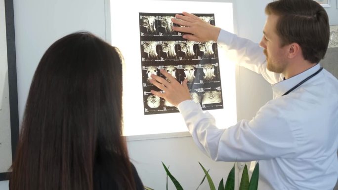 脊椎医生给病人看背部的x光片。