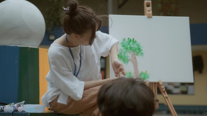 当所有的学生都感兴趣时，女老师在美术课上教学生开始用颜料画画。