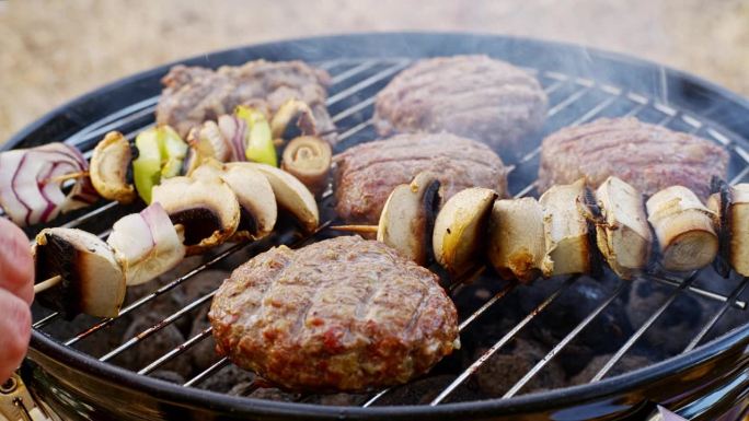 汉堡肉饼配香菇羊肉串，在圆形小烤架上用炭火和烟熏烤。