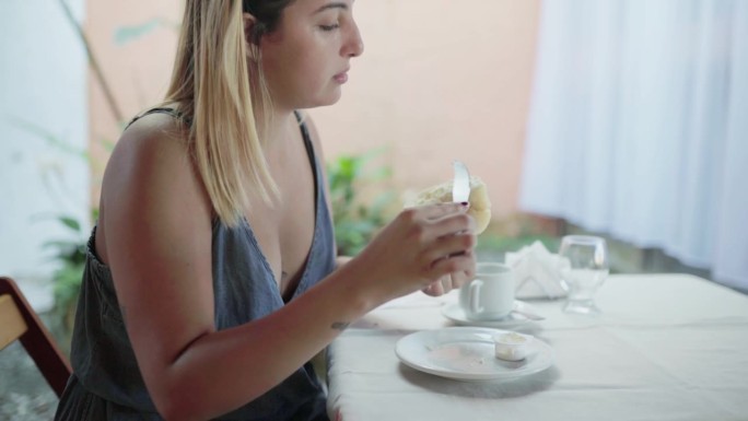 一位年轻女子在酒店用餐区坐下来吃早餐