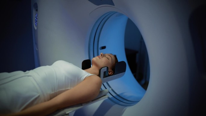 一名女性病人躺在CT或PET或MRI扫描床上，在机器扫描她的身体和大脑时在机器内移动。拥有高科技设备