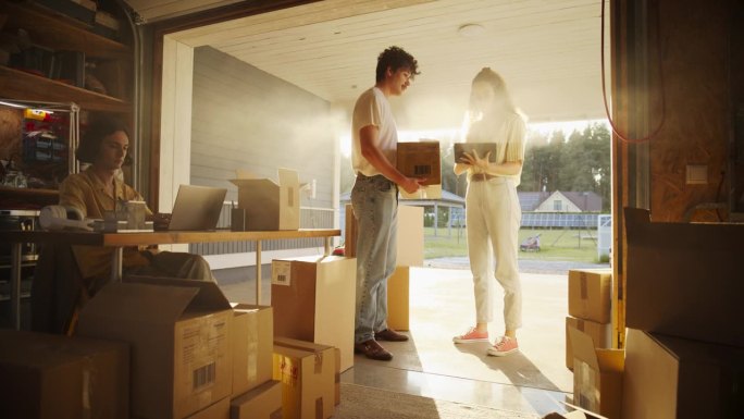 三个小企业主在车库工作。白人男性经理用笔记本电脑完成在线订单，西班牙裔女性联合创始人用平板电脑与负责