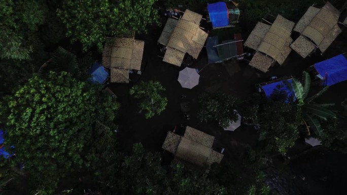 在森林覆盖的山间温泉河旁的露营地，帐篷和临时搭建的竹屋。无人机，航拍。