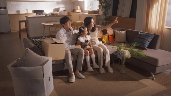 家庭搬进来:幸福的年轻韩国夫妇和他们的孩子坐在他们新买的公寓。美丽的一家三口幸福地拥抱在一起，讨论如
