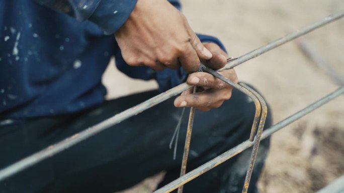 建筑工人将钢筋与钢筋网连接起来，作为线材建筑板的一部分，金属结构在现场退火钢捆绑，在室外建造房屋的工