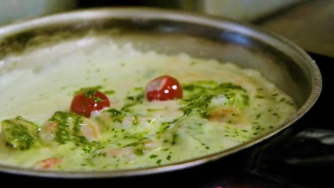 厨师搅拌白酱海鲜意面与虾和西红柿