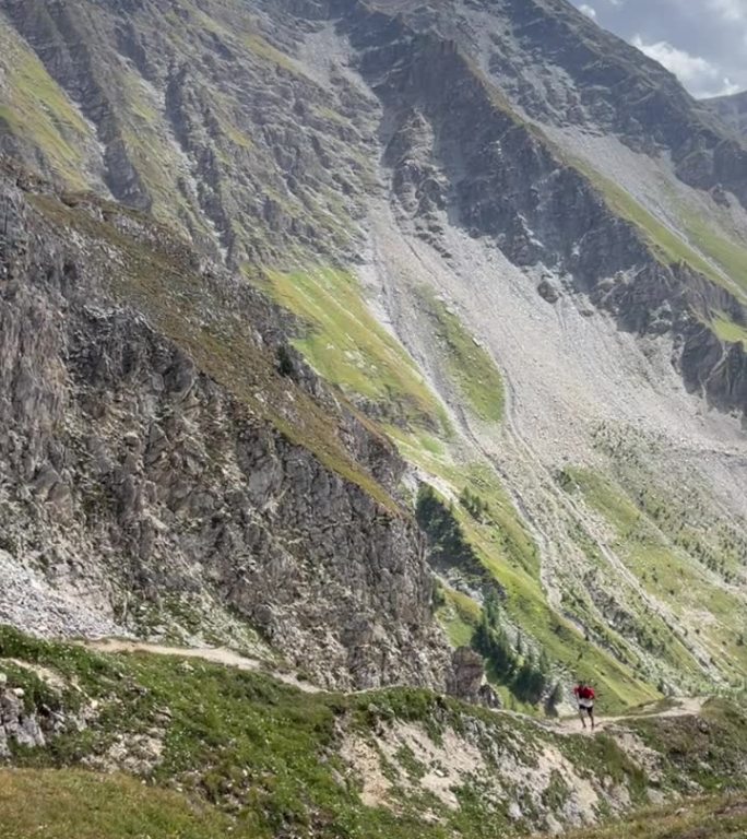 越野跑者攀登陡峭的小径，身后是落基山脉