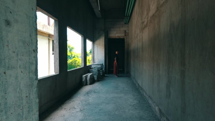 一个亚洲人站在一幢看起来阴森的建筑的小巷里