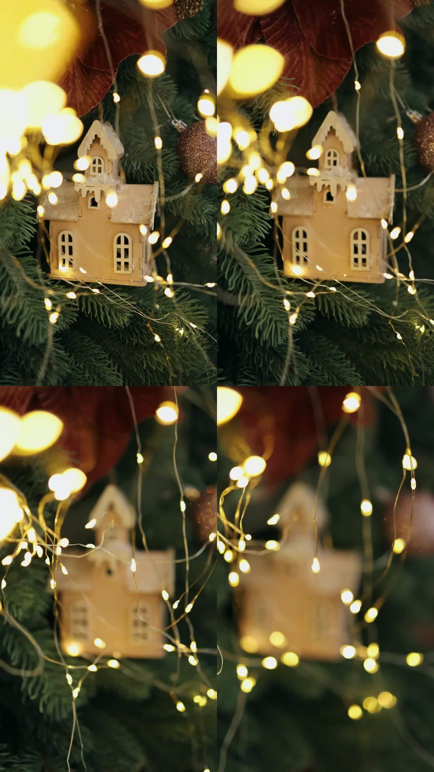 焦点通过灯泡转移到圣诞树上带玩具的花环上。圣诞树上的玩具木屋模型。垂直视频。散景
