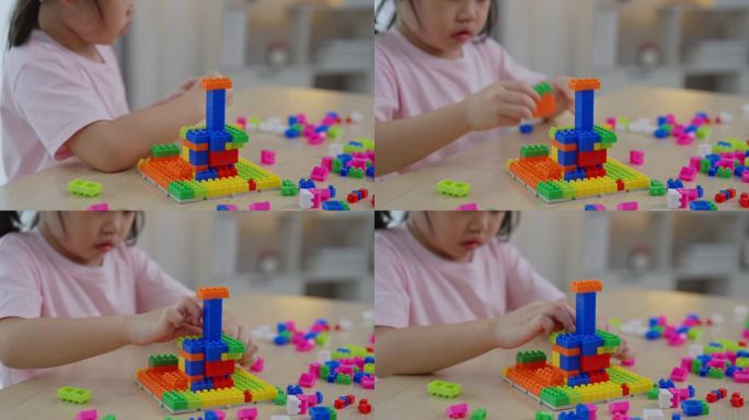 关闭了。快乐的亚洲女孩开心地笑着玩着五颜六色的乐高玩具，坐在客厅的桌子上，创造性地玩着乐高，搭建着五