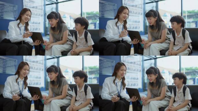 放松的亚洲母亲和孩子与愉快的老师用平板电脑讨论泰国国际学校的学费