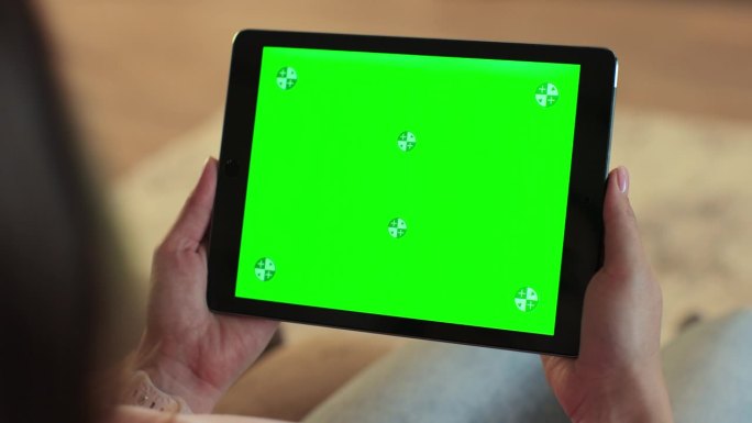 一个手持绿色屏幕的数字平板电脑的女人的特写。互联网在线，色度键屏概念。
