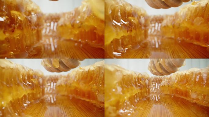 在一个充满蜂蜜的环境中，镜头在木勺下和蜂巢之间移动，从木勺上滴下蜂蜜。