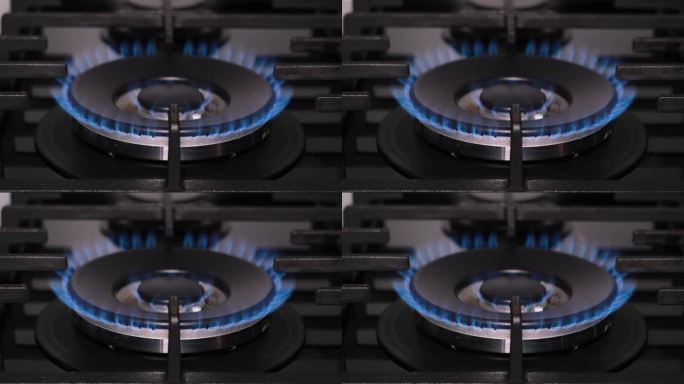 燃气灶点火的特写镜头。煤气在黑暗的房间里燃烧着蓝色的火焰
