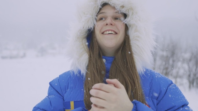 在大雪中漫步在斯堪的纳维亚村庄的蓝大衣女人正在思考真正的冬季童话