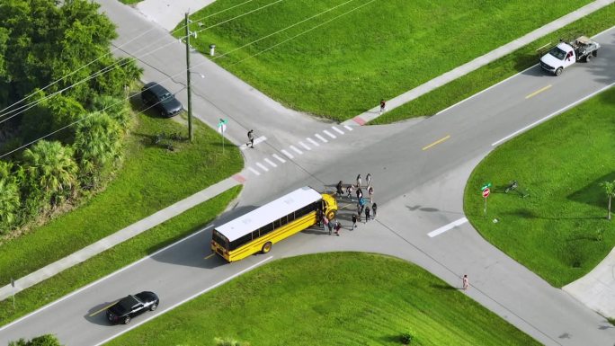 鸟瞰图清晨，美国黄色校车在人行道公交站接送孩子们上课。美国的公共交通